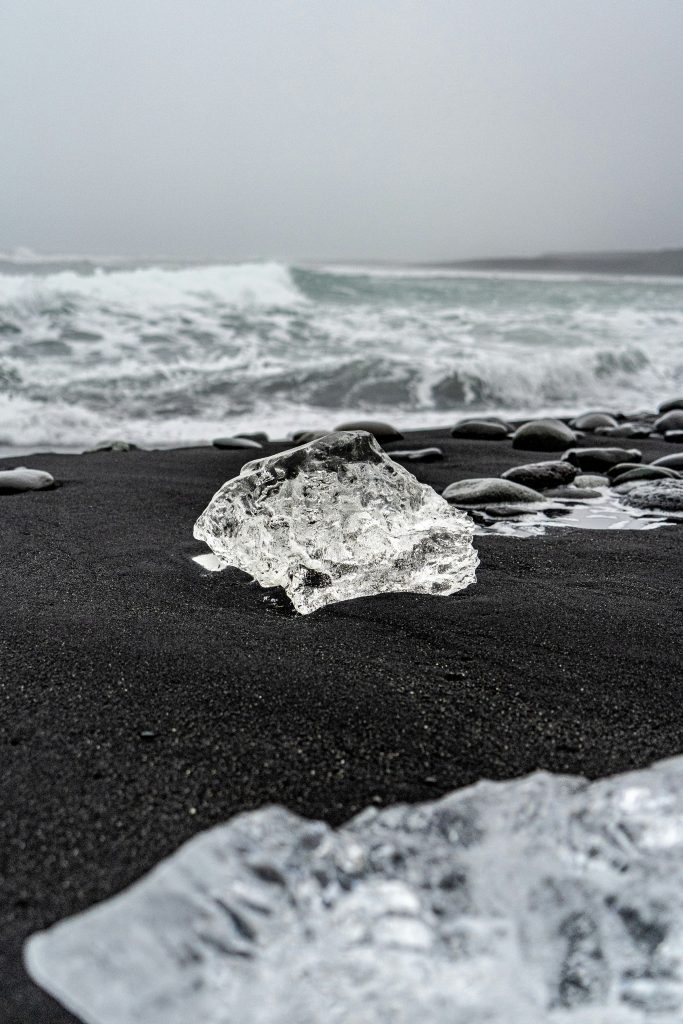 Cristal transparent sur plage de sable noir, au milieu des vagues.